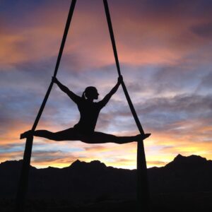 Silhouette of a woman practicing aerial yoga against a vibrant sunset sky in Las Vegas.